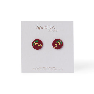 A pair of deep red stud earings with yellow and green wattle print made by Polymer clay